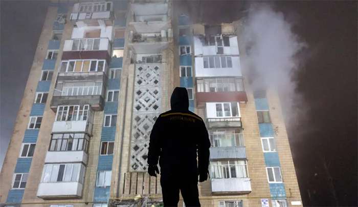 Άνδρας στέκεται μπροστά από ένα διαμέρισμα που βομβαρδίστηκε από τη Ρωσία στην Ουκρανία / REUTERS / Thomas Peter