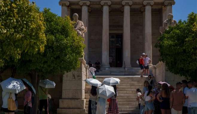Με ομπρέλες προστατεύονται από τον καυτό ήλιο οι τουρίστες που επισκέπτονται σημεία αρχαιολογικού ενδιαφέροντος στην Αθήνα  AP Photo/Petros Giannakouris